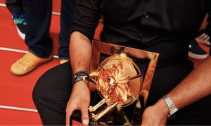 Fotografía en plano detalle de unas manos sosteniendo un trofeo de oro de Cannes Lions