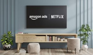 Fotografía del salón de una casa en la que se ve un mueble bajo, unos sillones sin respaldo y un televisor colgado en la pared en cuya pantalla aparecen los logos de Amazon Ads y Netflix