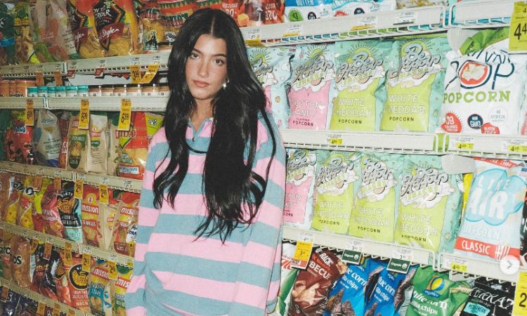 Charli D'amelio posing with her snacks brand calld Be Happy Snacks at a supermarket