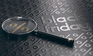 Lupa destaca símbolo de porcentaje sobre fondo negro con texto "black friday". Contexto de comercio y promociones.