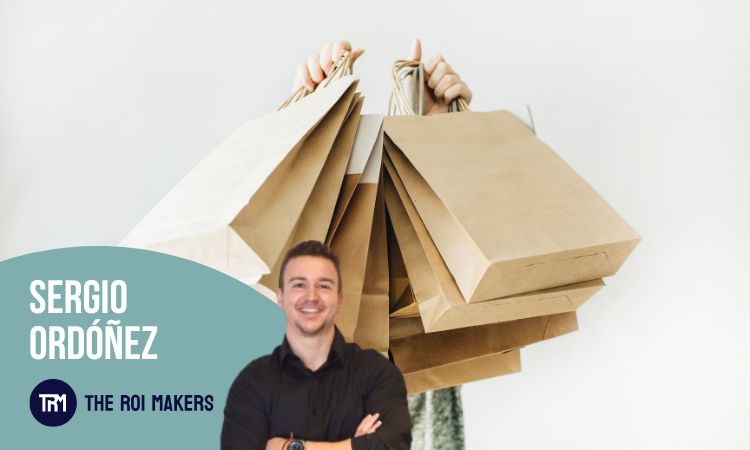 La imagen muestra a una persona sosteniendo varias bolsas de compras de papel kraft, lo que transmite una escena típica de compras, posiblemente relacionadas con rebajas o Black Friday. En primer plano, aparece una sección gráfica con el nombre “Sergio Ordóñez” y el logo de The ROI Makers, junto a la fotografía de un hombre joven, de brazos cruzados y sonriendo, asociado a esta marca o empresa.