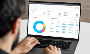 Persona usando un portátil que muestra gráficos y tablas de análisis de datos en un entorno de oficina. Marketing digital, analítica web.