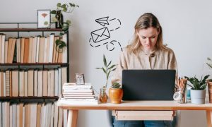 Imagen de una mujer en un estudio concentrada frente a su PC. Del ordenador sale un gráfico de un sobre junto a un avión de papel, haciendo referencia al email marketing del que habla el artículo.