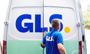 Empleado cierra furgoneta de reparto con logo "GLS" visible; envío rápido y logística eficiente en entorno urbano.