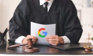 Fotografía de un juez vestido con su toga, sentado en su escritorio y sosteniendo unos documentos que muestran el logo de Google.