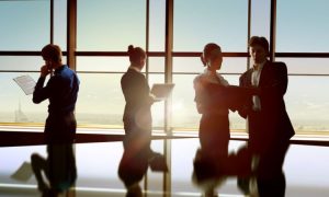 dos directivas y dos directivos pertenecientes al colectivo LGBTIQ+ en la oficina de un rascacielos acristalado