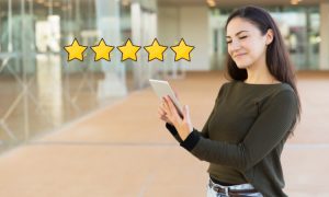 Imagen de una mujer joven, muy contenta, pulsando en su tablet, de la cual salen 5 estrellas amarillas.