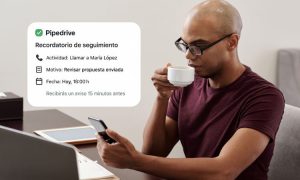 Imagen de un chico revisando sus notificaciones de Pipedrive en el móvil mientras se bebe un café.