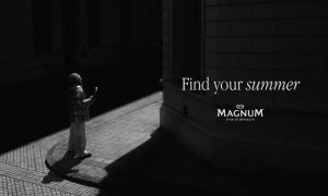 Creatividad de la campaña ‘Find Your Summer’ de LOLA MullenLowe para Magnum. Se trata de una fotografía en blanco y negro de la esquina de una calle, por ella entra un repentino rayo de sol que ilumina a una persona mientras come un helado Magnum. A la derecha, en la esquina oscura de la calle, se lee "Find your summer"