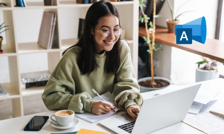 Fotografía de una mujer de unos 20 años en su oficina o despacho, usando su ordenador portátil para crear campañas. En la esquina superior derecha aparece el logo de Microsoft Advertising (antes Bing Ads)