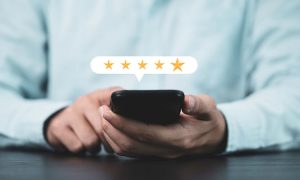 Imagen de un hombre sujetando un smartphone y una reseña online de 5 estrellas saliendo del mismo
