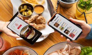Imagen de un restaurante con comida sobre la mesa y dos smartphones con la web del restaurante, para ilustrar el artículo sobre Cómo hacer la web de un restaurante en WordPress