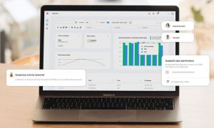 Portátil muestra gráficos de barras y notificaciones emergentes en pantalla. Entorno de oficina. Texto: "Suspicious activity detected" y "Suspend user permissions".