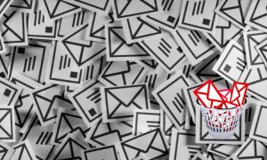Sobres de correo apilados; algunos rojos en una papelera. Contexto: saturación de correos electrónicos, simbolizando la necesidad de filtrar mensajes.