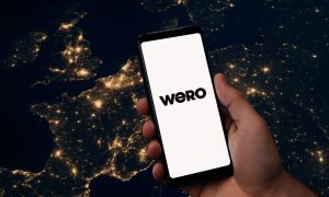 a hand with a cell phone, over a map of france, germany, netherlands, belgium... at night. Wero logo included